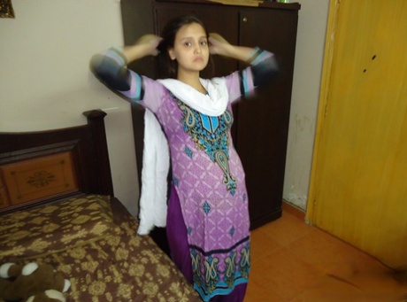 Pregnant Indian girl moisturizes after a shower before getting dressed 77442676