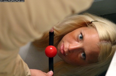 Platinum blonde girl is bound with rope while ball gagged in cramped quarters 47825613