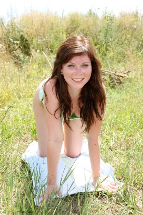Redhead with freckles toys her shaved teen pussy in the grass beside dirt road 49169784