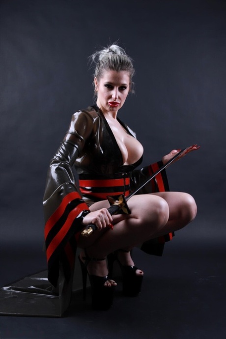 Platinum blonde solo model wields a sword while outfitted in a latex costume 10651872